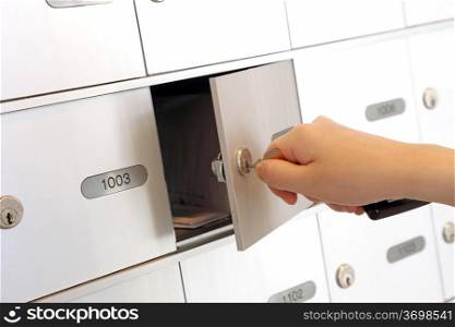 Woman holding key and opening mailbox