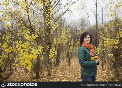 Woman holding leaves in forest, portrait