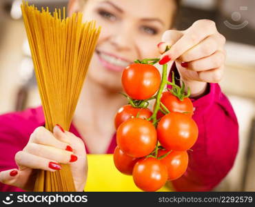 Woman holding long pasta macaron and fresh organic delicious tomatoes about to cook spaghetti.. Woman holding pasta and tomatoes