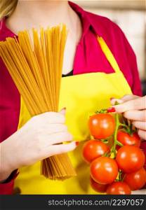 Woman holding long pasta macaron and fresh organic delicious tomatoes about to cook spaghetti.. Woman holding pasta and tomatoes