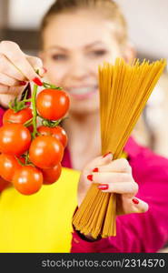 Woman holding long pasta macaron and fresh organic delicious tomatoes about to cook spaghetti.. Woman holding pasta and tomatoes