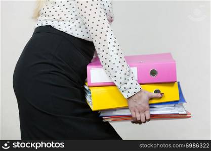 Woman holding many heavy colorful binders with documents. Office, bookkeeping objects concept.. Woman holding heavy colorful binders with documents