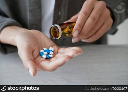 Woman holding medicine bottle pour pills into palm to take dietary supplements, vitamins or medicines, close up of female taking painkiller or sleeping tablets. Health care and wellness. Woman pour pills into palm to take dietary supplements, vitamins or medicines. Health care, wellness