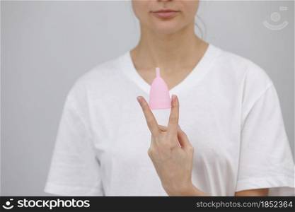woman holding menstrual cup between her fingers. Feminine hygiene alternative product instead of tampon during period. Menstruation, critical days, women periods. Zero waste, eco, ecology. woman holding menstrual cup between her fingers. Feminine hygiene alternative product instead of tampon during period. Menstruation, critical days, women periods. Zero waste, eco, ecology.