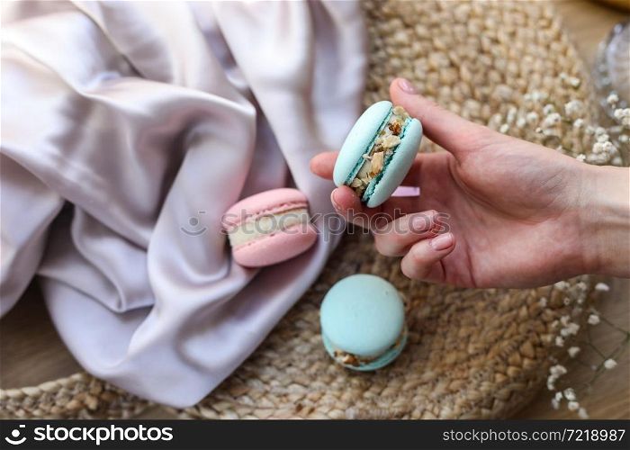 woman holding mint french macaroon or macaron cookie and a white flowers on a cloth background. Natural fruit and berry flavors, creamy stuffing for valentines mother day easter with love food.. woman holding mint french macaroon or macaron cookie and a white flowers on a cloth background. Natural fruit and berry flavors, creamy stuffing for valentines mother day easter with love food