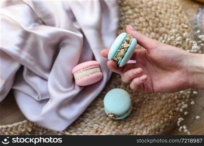 woman holding mint french macaroon or macaron cookie and a white flowers on a cloth background. Natural fruit and berry flavors, creamy stuffing for valentines mother day easter with love food.. woman holding mint french macaroon or macaron cookie and a white flowers on a cloth background. Natural fruit and berry flavors, creamy stuffing for valentines mother day easter with love food