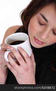 Woman holding mug of coffee to face
