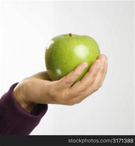 Woman holding out green apple in hand.