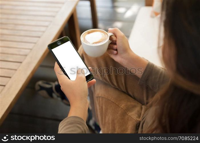 woman holding phone and coffee in cafe