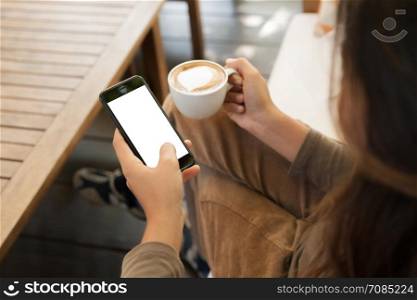 woman holding phone and coffee in cafe