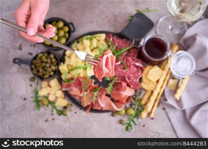 Woman holding piece of prosciutto ham on a fork standing at domestic kitchen.. Woman holding piece of prosciutto ham on a fork standing at domestic kitchen
