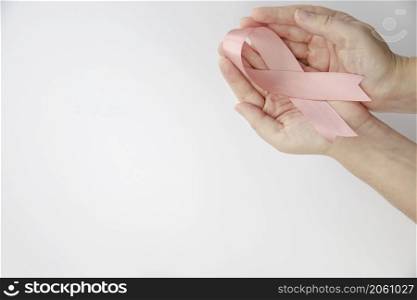 Woman holding pink ribbon on gray background, top view. Breast cancer awareness concept, Female health care concept copy space space for text. Woman holding pink ribbon on gray background, top view. Breast cancer awareness concept, Female health care concept copy space