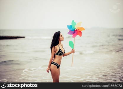 Woman Holding Pinwheel Toy While Walking At Beach Against Sky