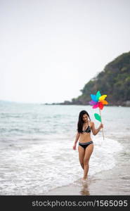 Woman Holding Pinwheel Toy While Walking At Beach Against Sky