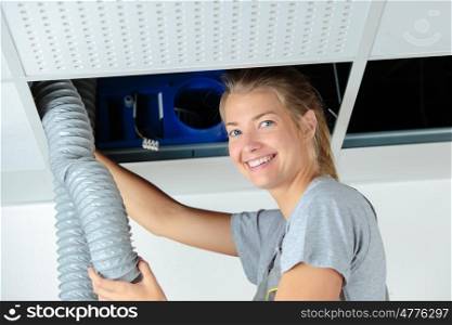 woman holding pipe overhead in roofspace