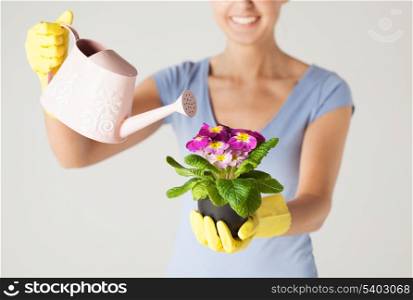 woman holding pot with flower and watering can
