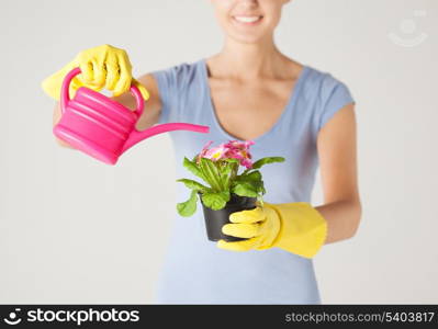 woman holding pot with flower and watering can