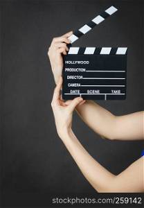 Woman holding professional film slate, movie clapper board. Hollywood production objects concept. Studio shot on black background.. Woman holding professional film slate