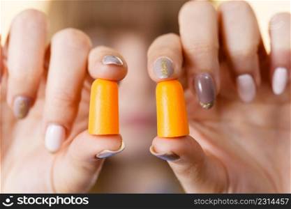 Woman holding protective ear plugs. Getting rid on noise in loud place, hearing protection concept.. Woman holding protective earplugs