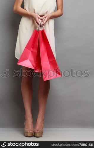 Woman holding red paper shopping bags. Elegant lady bright dress buying clothes. Sale and retail.