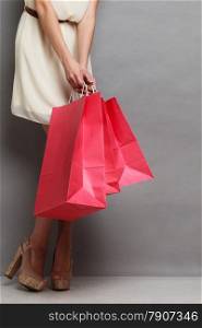 Woman holding red paper shopping bags. Elegant lady bright dress buying clothes. Sale and retail.