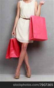 Woman holding red paper shopping bags. Elegant lady bright dress buying clothes. Sale and retail.