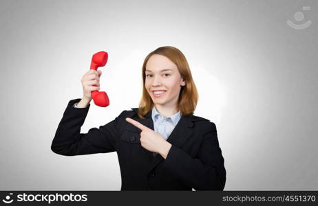 Woman holding red phone handset. Young businesswoman with red phone receiver in hands