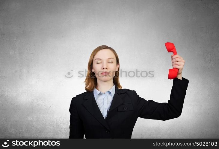 Woman holding red phone handset. Young businesswoman with red phone receiver in hands