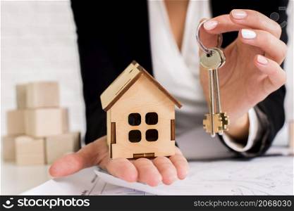 woman holding set keys with wooden house