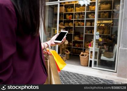 Woman holding shopping bag and using smartphone for shopping online, shopping concept.