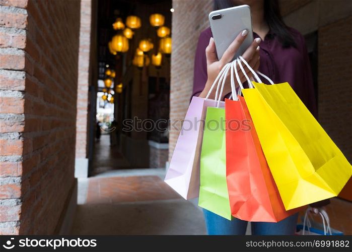 Woman holding shopping bag and using smartphone for shopping online, shopping concept.