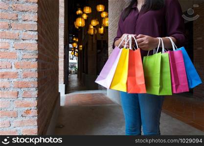 Woman holding shopping bag while walking on vintage street, shopping concept.