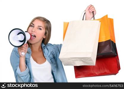Woman holding shopping bags and shouting into a loudspeaker