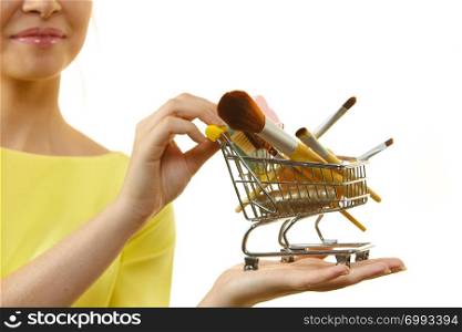 Woman holding shopping cart full of beauty accessories like various make up brushes.. Woman holding shopping cart with make up brushes