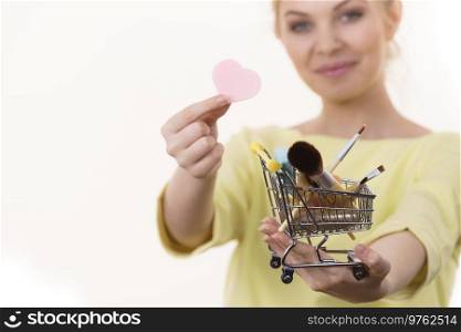 Woman holding shopping cart full of beauty accessories like various make up brushes.. Woman holding shopping cart with make up brushes