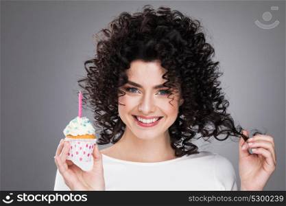 Woman holding small cake. Beautiful young woman holding small cake with colorful candle. Birthday, holiday. Studio portrait