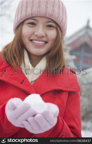 Woman Holding snowball outside in park