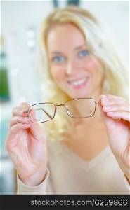 Woman holding spectacles to foreground