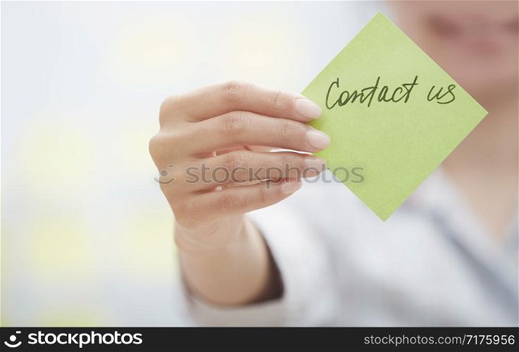 Woman holding sticky note with Contact us text