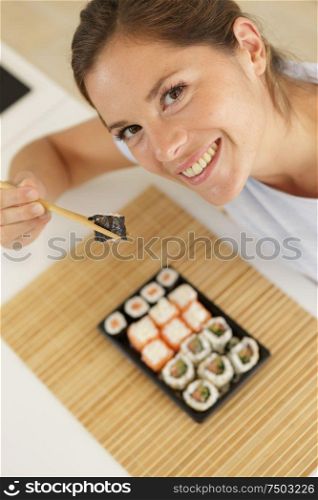 woman holding sushi between chopsticks