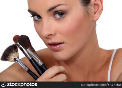 woman holding three make up brushes