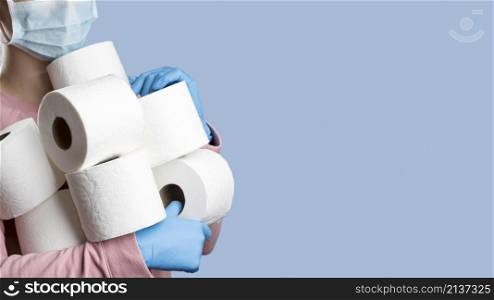woman holding toilet paper rolls while wearing surgical gloves medical mask