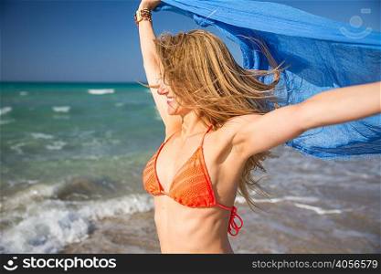 Woman holding up scarf on beach