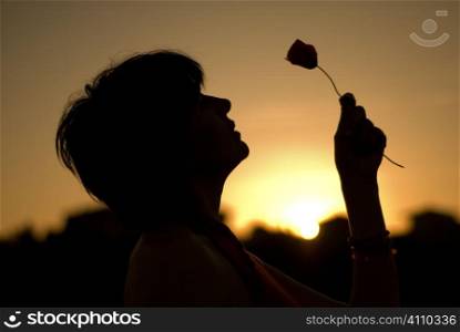 Woman holding wildflower at sunset, Granada, Andalusia