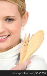 woman holding wooden spoon and fork