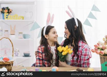 woman holding yellow tulips bouquet embracing her daughter easter day celebration