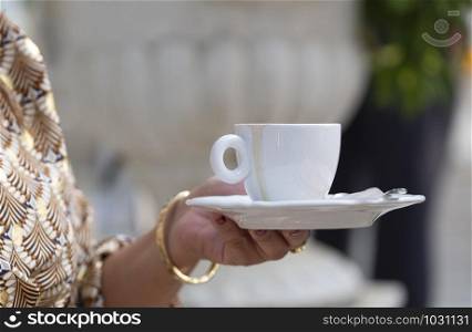 woman holds a white cup of coffee