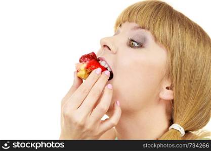 Woman holds cake cupcake in hand taking a huge bite out of dessert, eating unhealthy junk food. Sweetness indulging and fattening concept. Woman eating cupcake sweet food