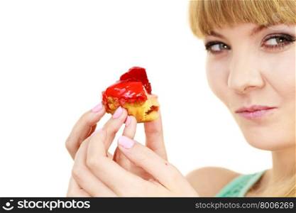 Woman holds cake cupcake in hand taking a huge bite out of dessert, eating unhealthy junk food. Sweetness indulging and fattening concept