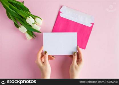 Woman holds greeting card in her hands. Gift for spring holiday. Bouquet of fresh tulips on pink background.. Woman holds greeting card in her hands. Bouquet of fresh tulips on pink background.